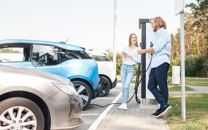 Divi jauni cilvēki apmaksā elektroauto uzlādi ar telefonu